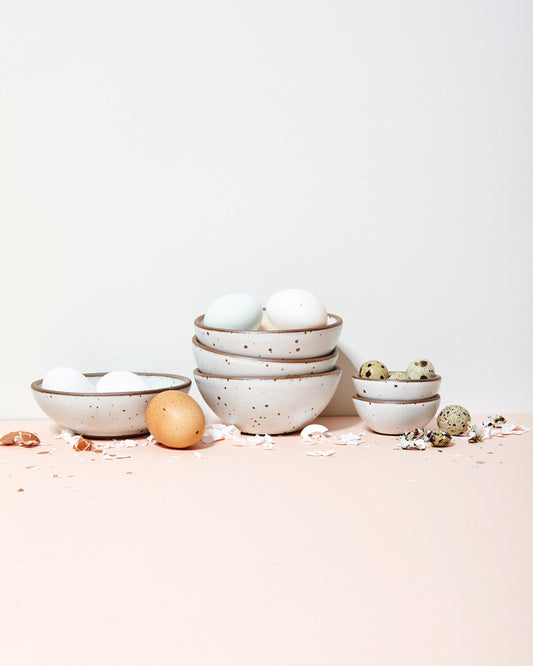 Bowls by East Fork filled with white, brown, and speckled eggs.