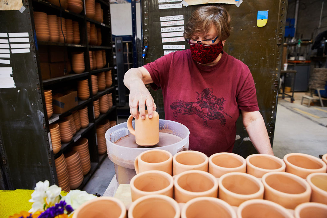 Talea wearing her mask and dipping The Mug in glaze