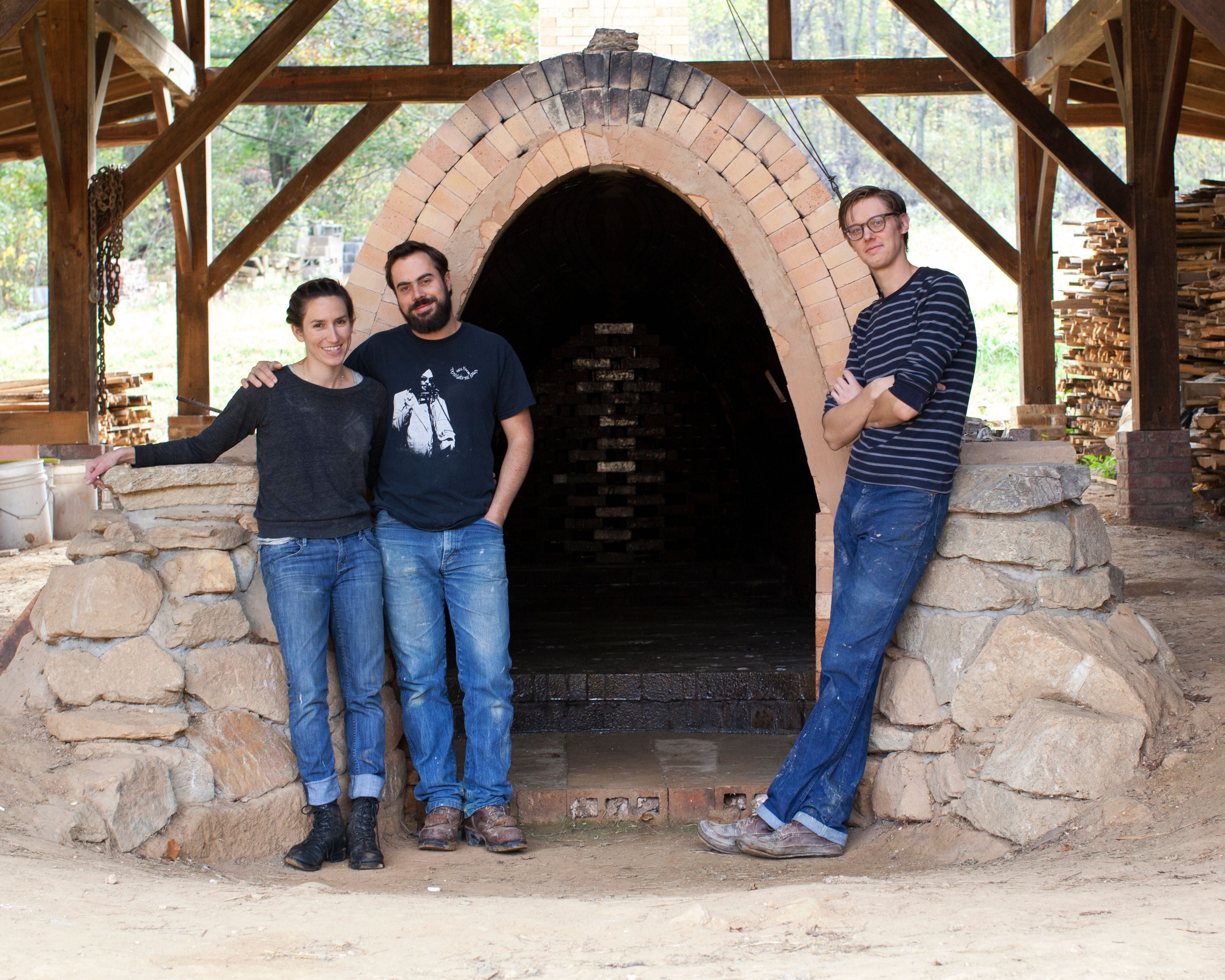 Connie and Alex Matisse and John Vigeland stand in front of the opening of the original wood fired kiln