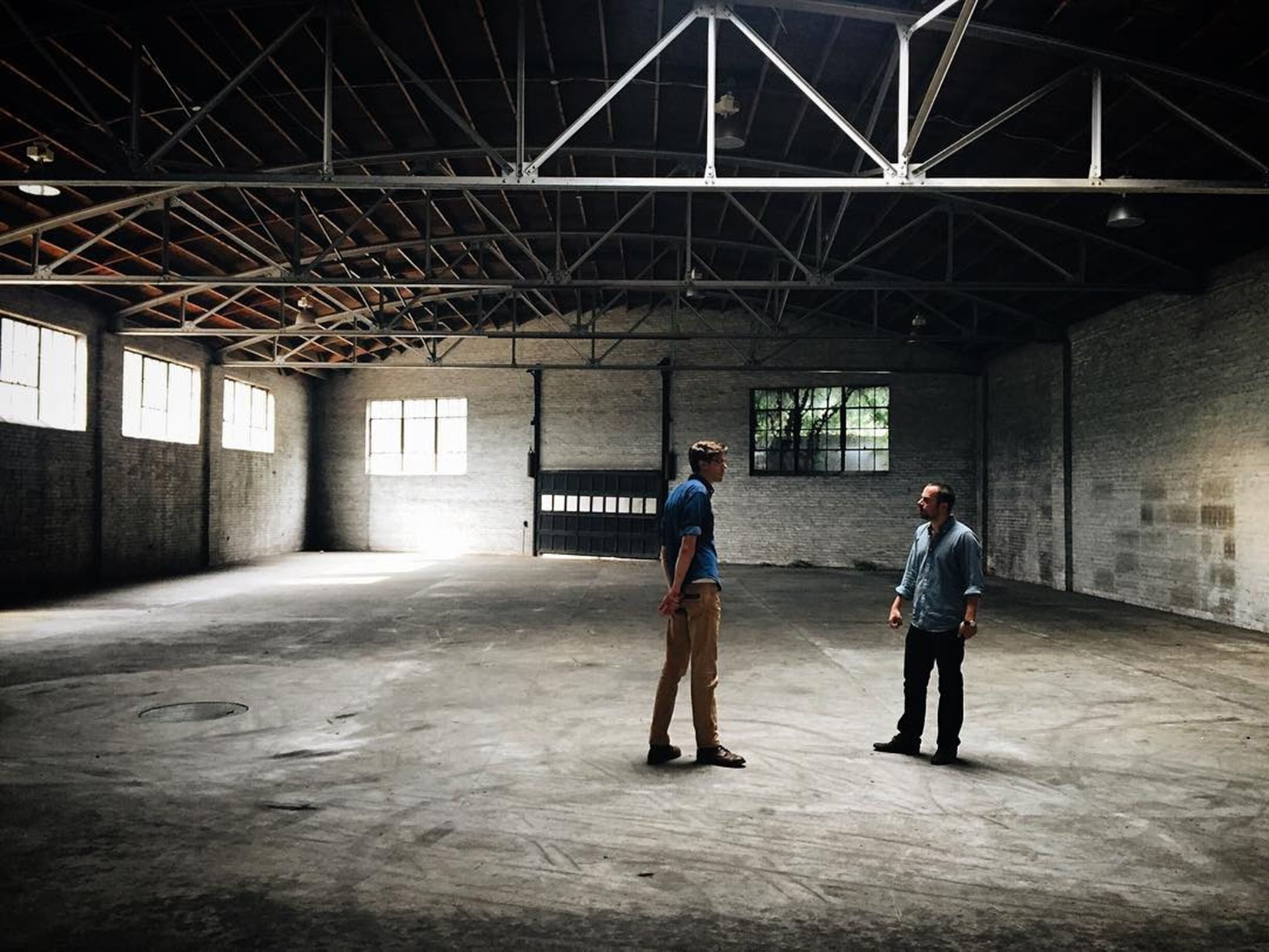 Alex and John stand in an empty factory building