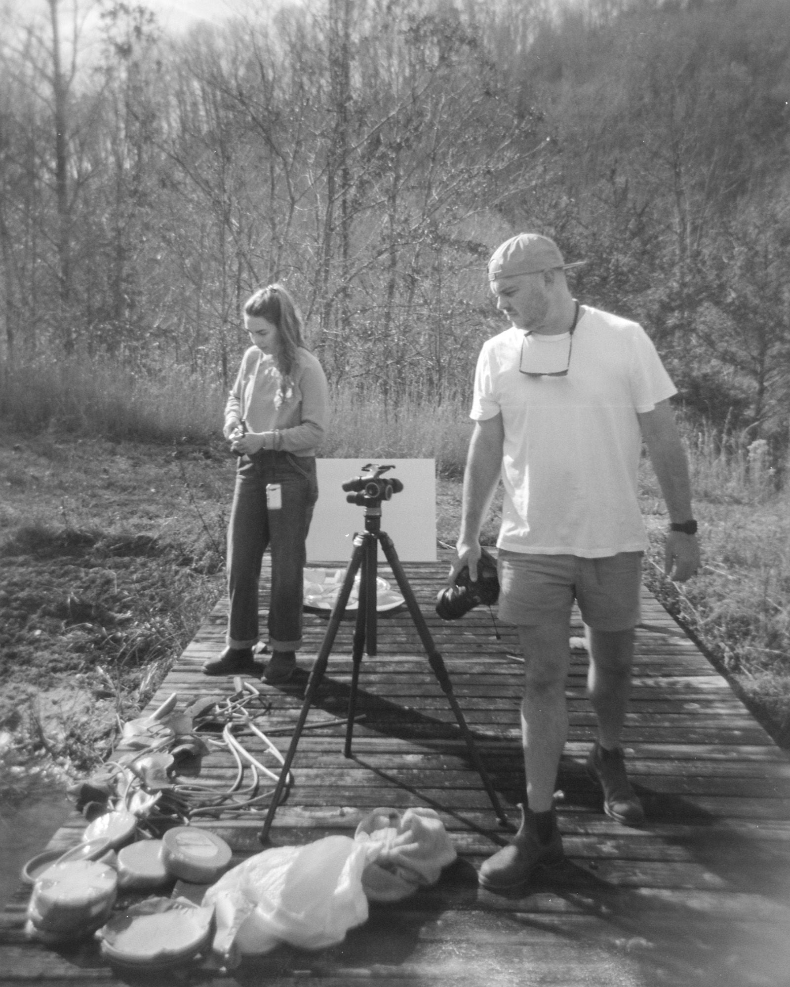 A black and white photo of a woman and a man outside holding cameras