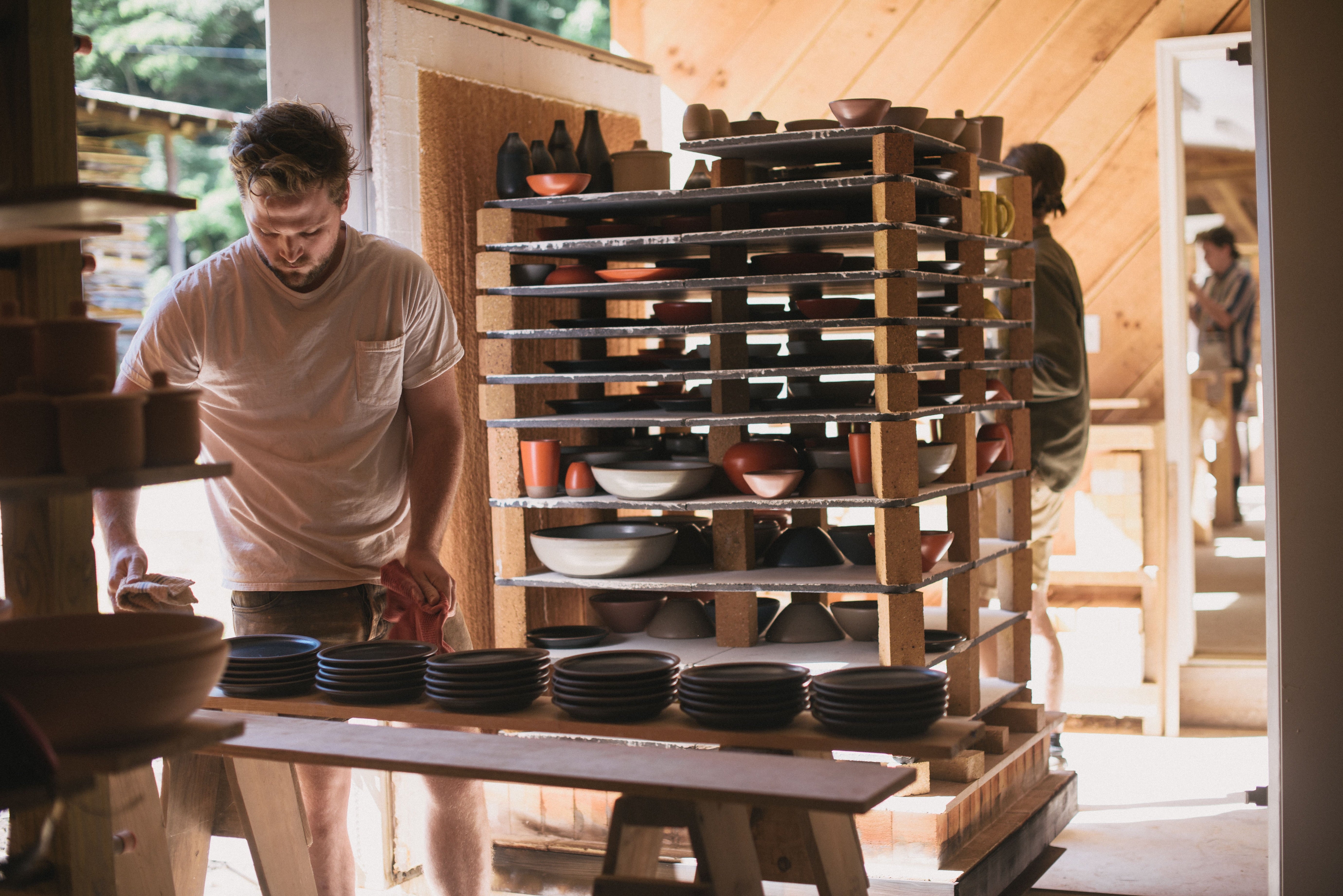 People unload pots from shelves that recently came out of the kiln