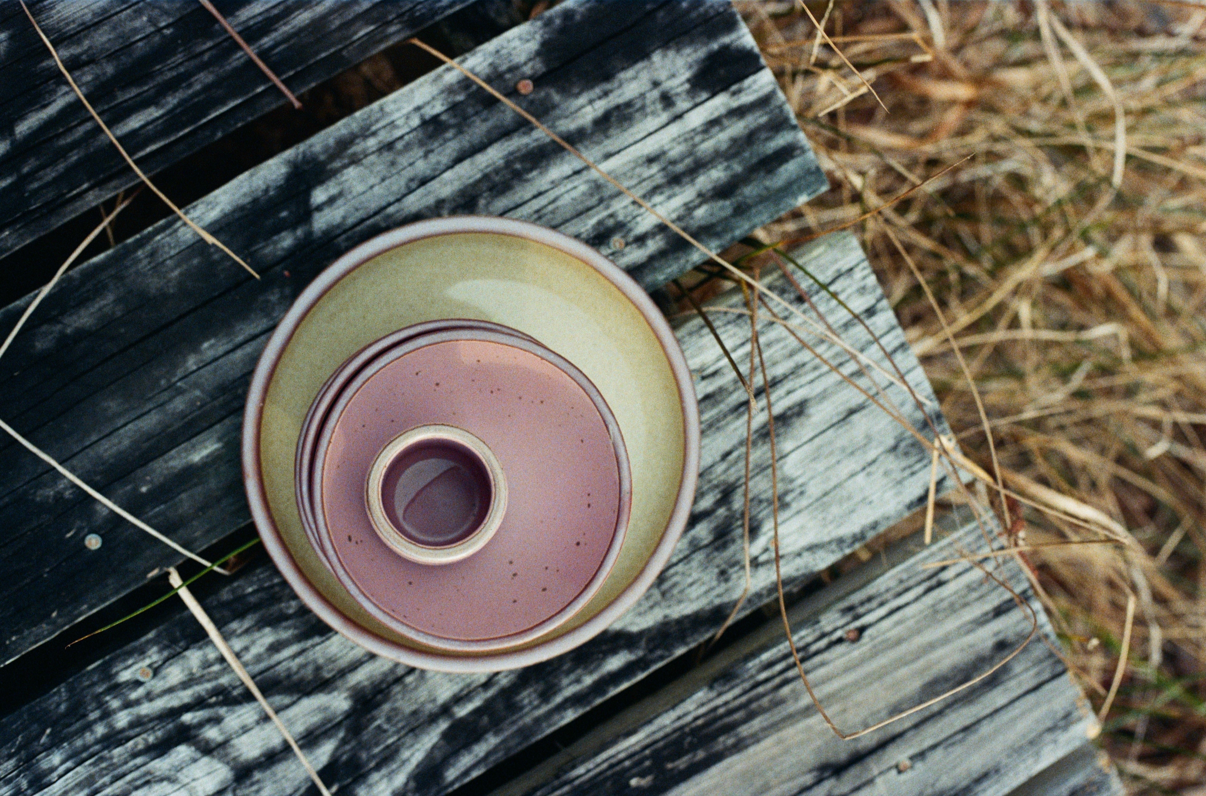 Pale green and pink pottery in a stack on top of a wooden dock outside
