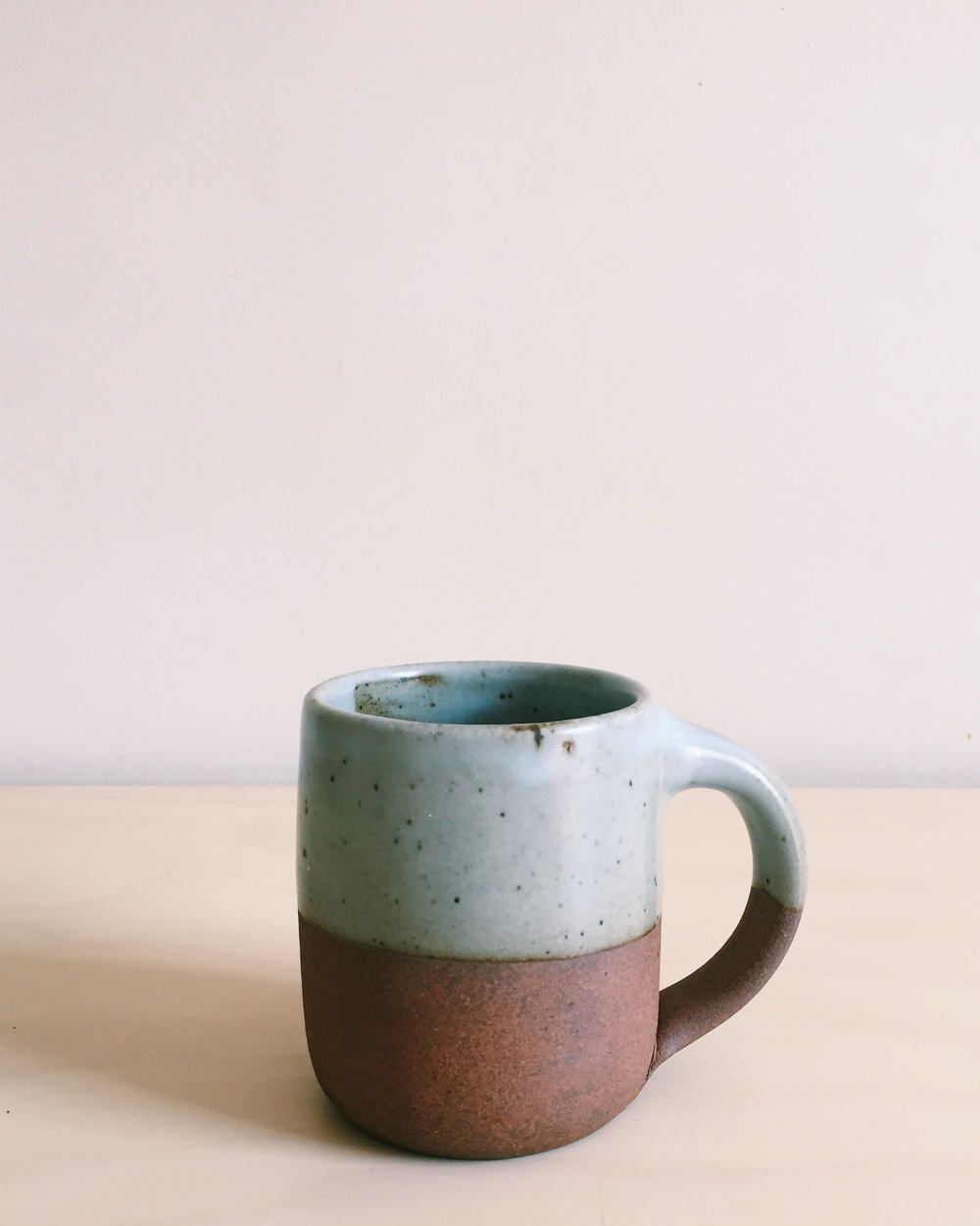 A short East Fork Mug with a pastel earthy blue color, and unglazed bottom